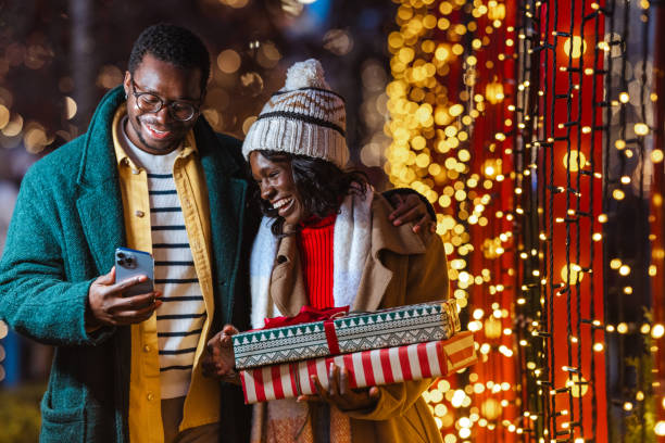 istock Couple enjoying a festive Christmastime evening outdoors and using a smartphone 2181760196
