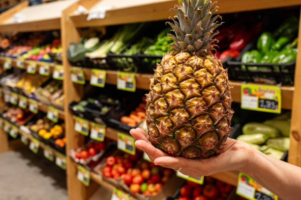 istock A person is holding a pineapple in a grocery store. 2181760955