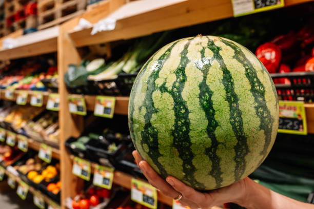 istock A person is holding a watermelon in a grocery store. 2181760963