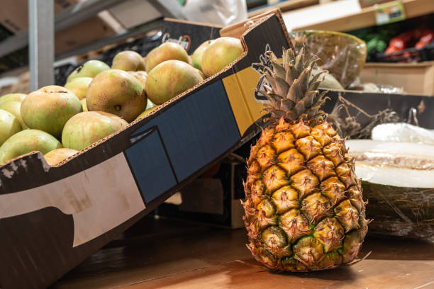 A pineapple sits on a table next to a cardboard box that says
