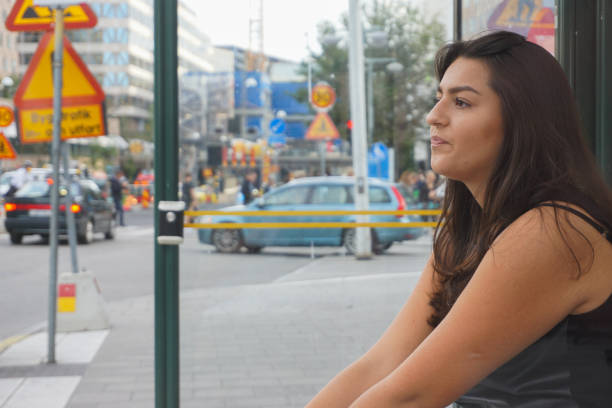 A young woman sits at a bus stop
