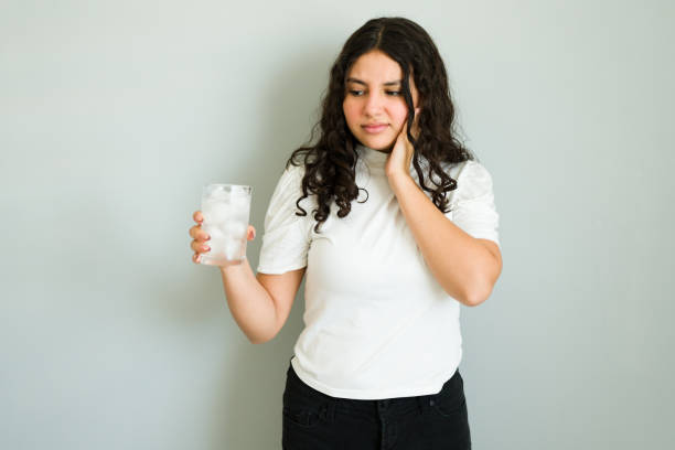 Common dental issue: teenager experiences dentin hypersensitivity from drinking a cold beverage
