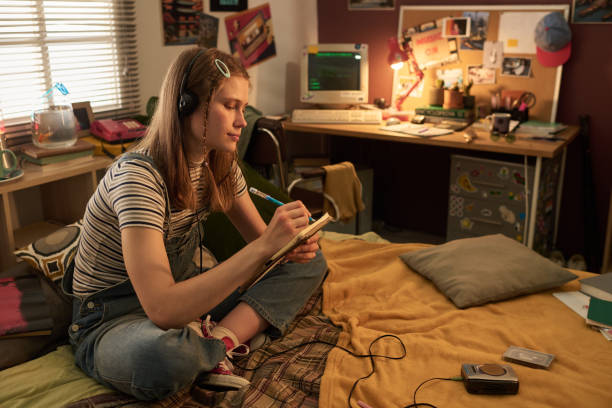 istock Young Woman Writing in Notepad While Listening to Music 2181766953