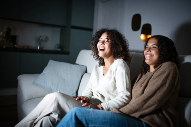 istock Sisters watching TV on sofa: Smiling and laughing 2181768139