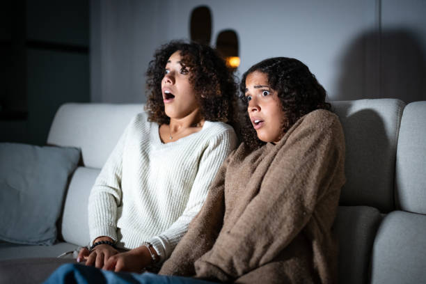 istock Sisters watching TV on sofa: Scary movie 2181768240
