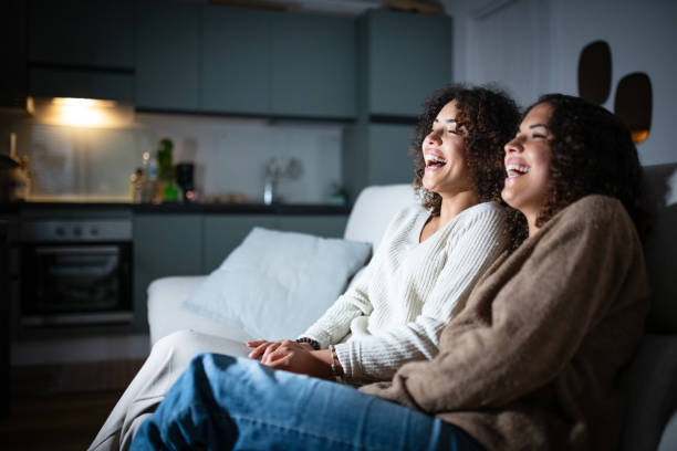 istock Sisters watching TV on sofa: Smiling and laughing 2181768295