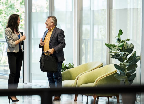 istock Two businesspeople talking while standing in modern office lobby 2181769635