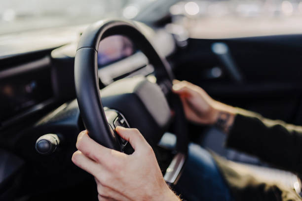 istock Young man inside his car, driving a luxury car with both hands on the wheel. 2181773471