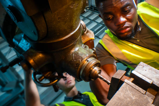 istock Focused industrial worker operating a heavy-duty drill in a workshop. The image captures precision, skill, and attention to detail, as well as the importance of safety equipment like gloves and vests. 2181773556