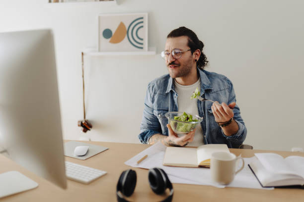 istock Young man working at home office and eating salad 2181774185