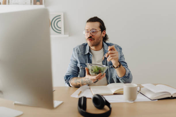 istock Young man working at home office and eating salad 2181775074