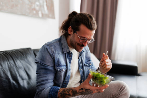 istock Man eating salad and drinking water at home 2181775112