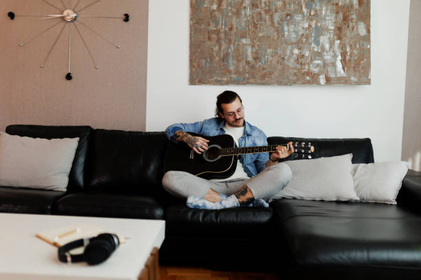 istock Young man learning to playing guitar at home 2181775893