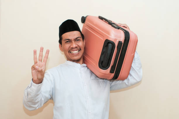 istock Excited Southeast Asian Muslim man carrying suitcase while showing three finger, Isolated on white background. 2181776221