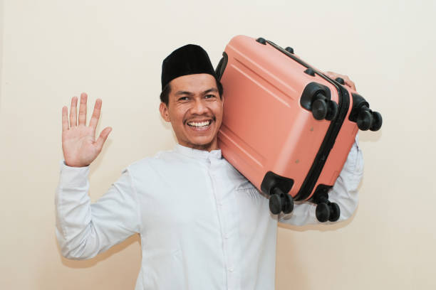 Excited Southeast Asian Muslim man carrying suitcase while showing five finger, Isolated on white background.