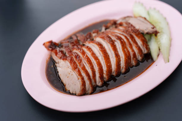 Sliced roasted duck with sauce, served on a plate with cucumber slices.