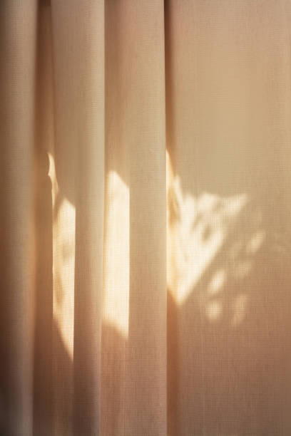 Beige vertical background - sun rays on curtain folds