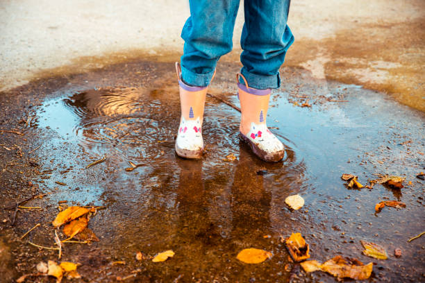 Child Splashing rubber boots in rain puddle