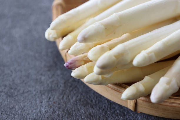 istock White asparagus on a bamboo colander isolated on a gray background. 2181792540