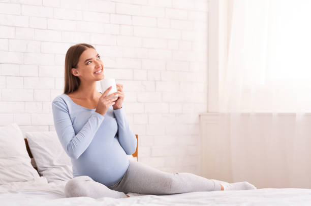 istock Happy Pregnant Lady Having Coffee Sitting In Bed 2181795458
