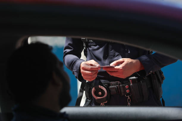 Members of the National Civil Police of El Salvador (PNC) search a motorist after walking through the streets following an order to place a military fence in Colonia 10 de Octubre, El Salvador