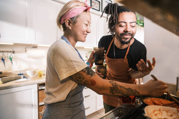 Young Mixed race couple preparing pasta sauce dish in home kitchen