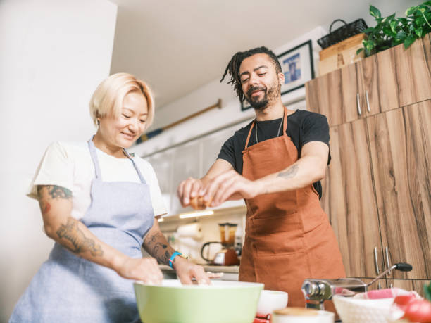istock Young Mixed race couple preparing pasta dish in home kitchen 2181802121