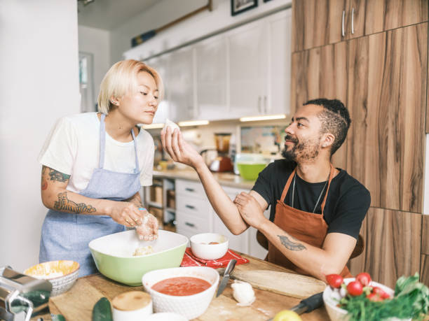 istock Young Mixed race couple preparing pasta dish in home kitchen 2181802136