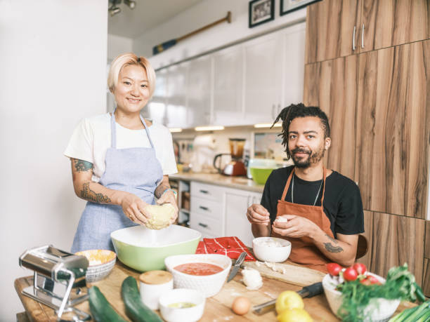 istock Young Mixed race couple preparing pasta dish in home kitchen 2181802152