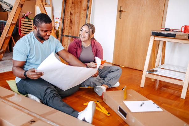 istock Young couple assembling shelf in their new home looking at drawing and consulting 2181809185