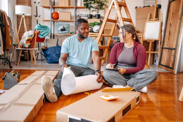 istock Young couple assembling shelf in their new home looking at drawing and consulting 2181809190