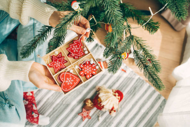 istock Hand holds box of red Christmas ornaments by tree. 2181811278