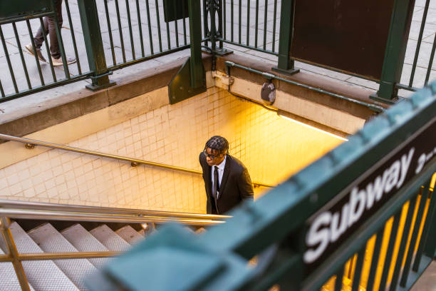 A businessman wearing a suit descending into a subway station during the day in an urban setting.