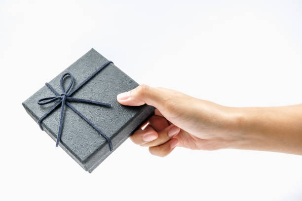istock A hand presenting a neatly wrapped black gift box with a ribbon, symbolizing surprise and celebration. 2181812662