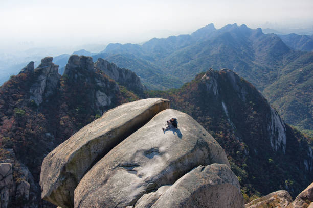 Seoul, Korea - October24th 2024, A Hiker taking a break on big rock of Baegundae Peak Bukhansan Seoul Korea. 서울 북한산 백운대