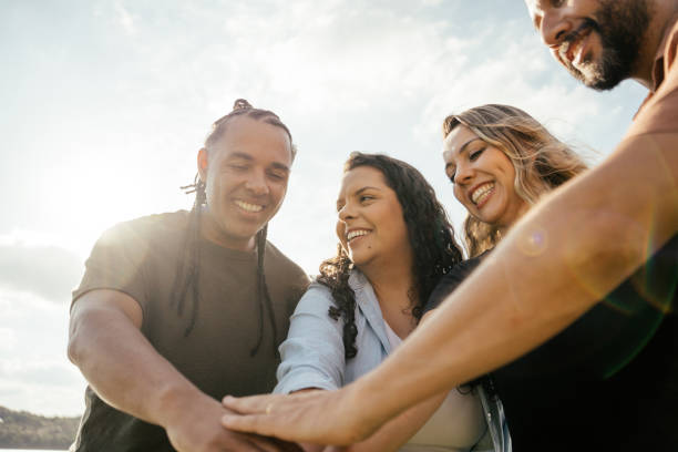Low angle view of young college students stacking hands against white background