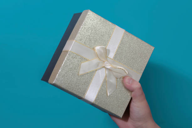 istock Boy's hand with a classic box with a gift. Bow on the box. blue background. Close-up 2181814918