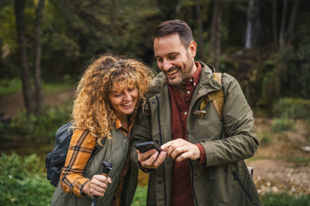 istock husband and wife stand in front waterfall and use cellphone 2181815492