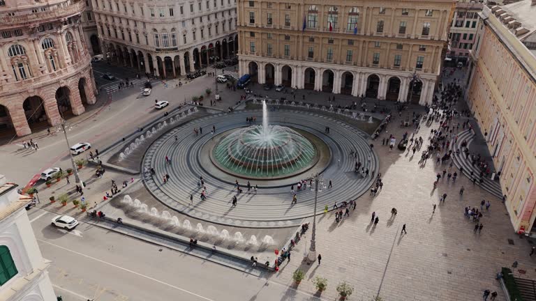 A busy fountain square surrounded by historic buildings in the heart of genoa, aerial view