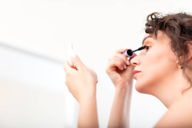 Woman applying mascara in mirror