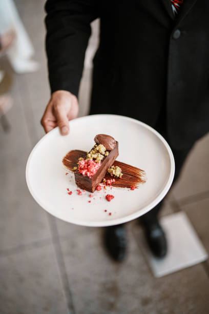 Male restaurant server holding slice of chocolate torte