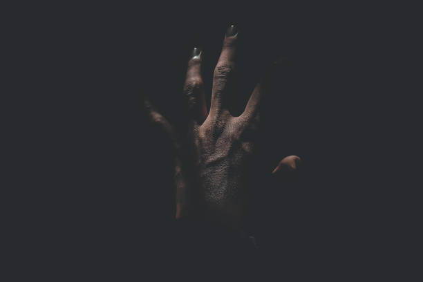 Male hand reaching for light in darkness on isolated black background. Selective focus on hand