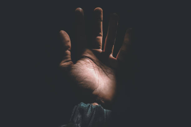 istock Male hand reaching for light in darkness on isolated black background. Selective focus on hand 2181834032