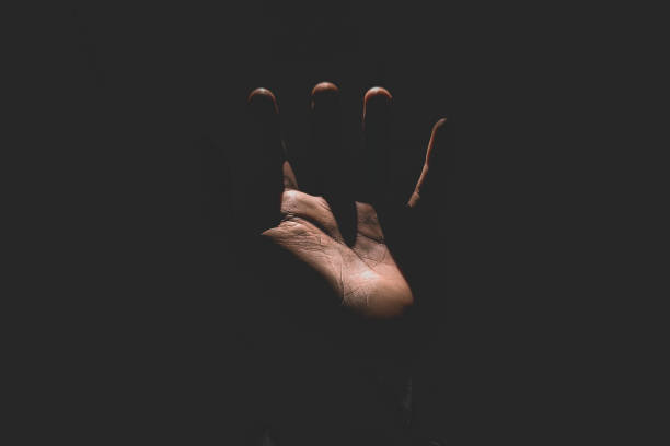 istock Male hand reaching for light in darkness on isolated black background. Selective focus on hand 2181834041