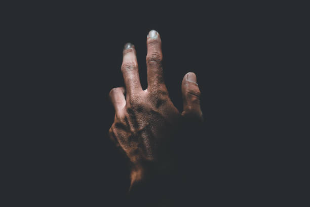 istock Male hand reaching for light in darkness on isolated black background. Selective focus on hand 2181834048