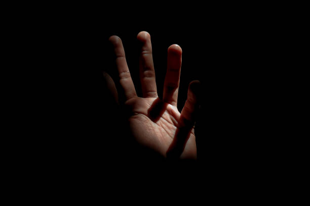 istock Male hand reaching for light in darkness on isolated black background. Selective focus on hand 2181834075