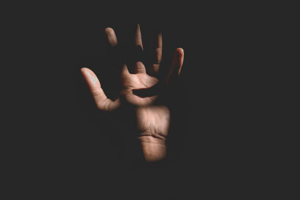 istock Male hand reaching for light in darkness on isolated black background. Selective focus on hand 2181834093