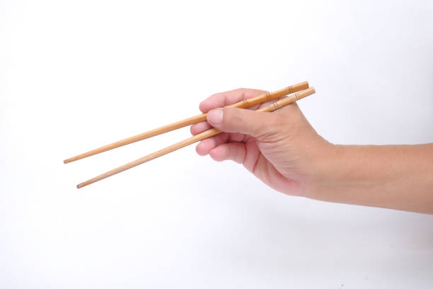 Hand holding bamboo chopsticks over white background