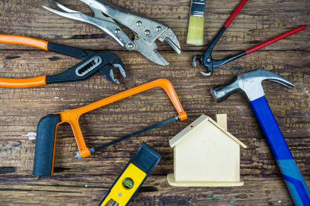 istock The image shows various hand tools arranged around a small house model with two band-aids crossed on its front, all set on a wooden surface. It's a great representation of home repair and maintenance. 2181843286