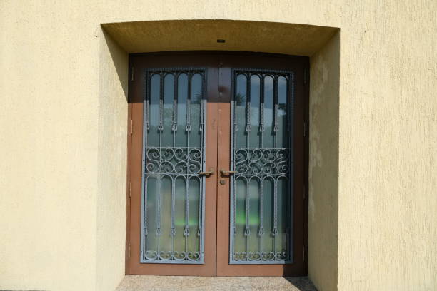 istock Ornate double doors with decorative metalwork on a textured yellow wall, bathed in sunlight 2181843841